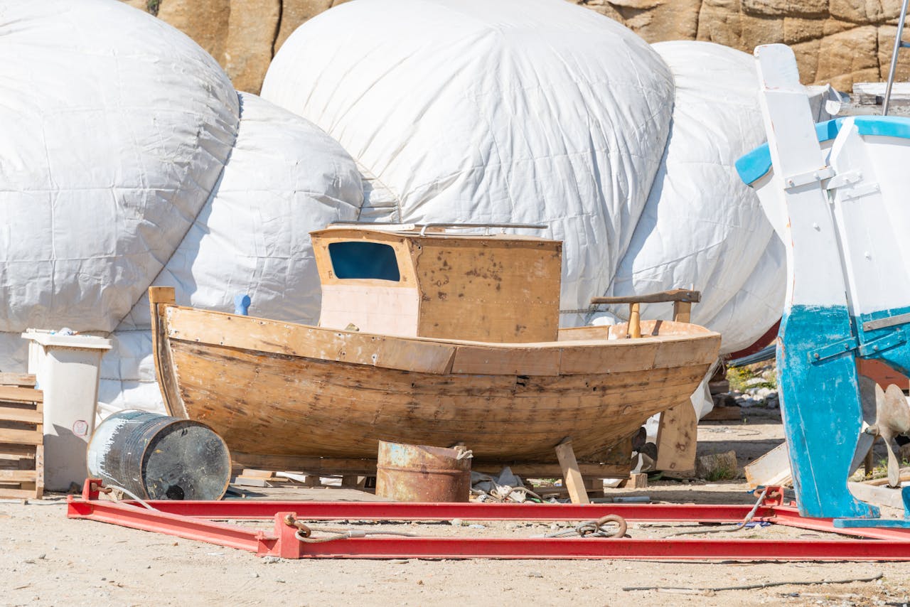 about-us Wooden fishing boat alongside covered boats in a sunny harbor repair area.