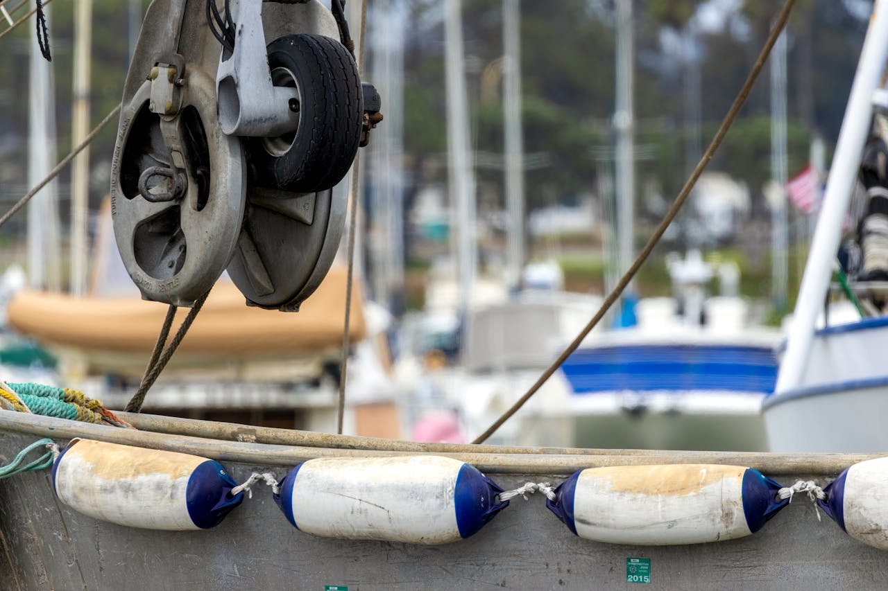 Detailed view of boat gear and ropes in a bustling marina backdrop.