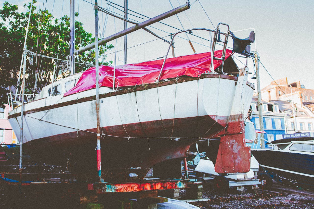 Rustic sailboat with pink tarp under maintenance in Cobh, Ireland harbor.
