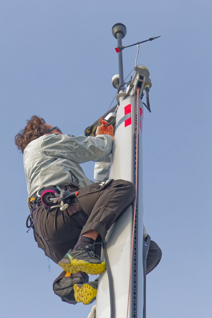 discover A skilled technician climbing a mast in Les Sables-d'Olonne, showcasing expertise in sailing technology.